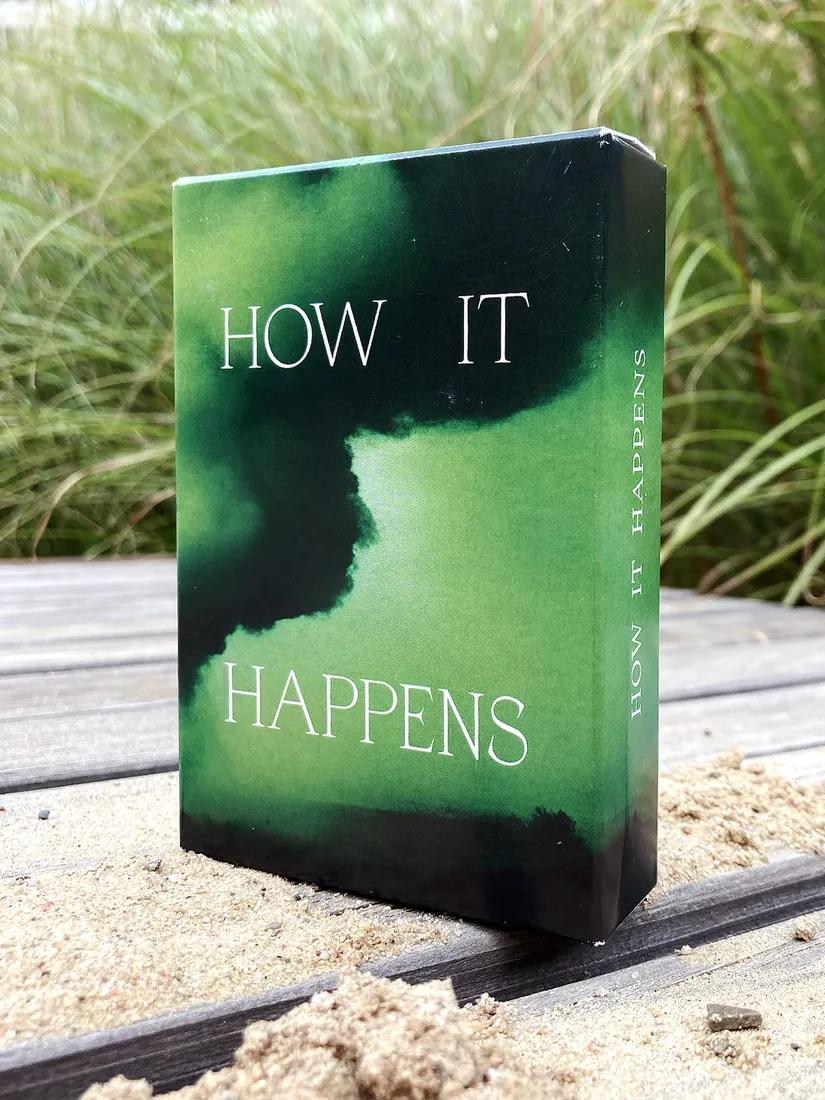 The How It Happens card deck standing on a boardwalk.
